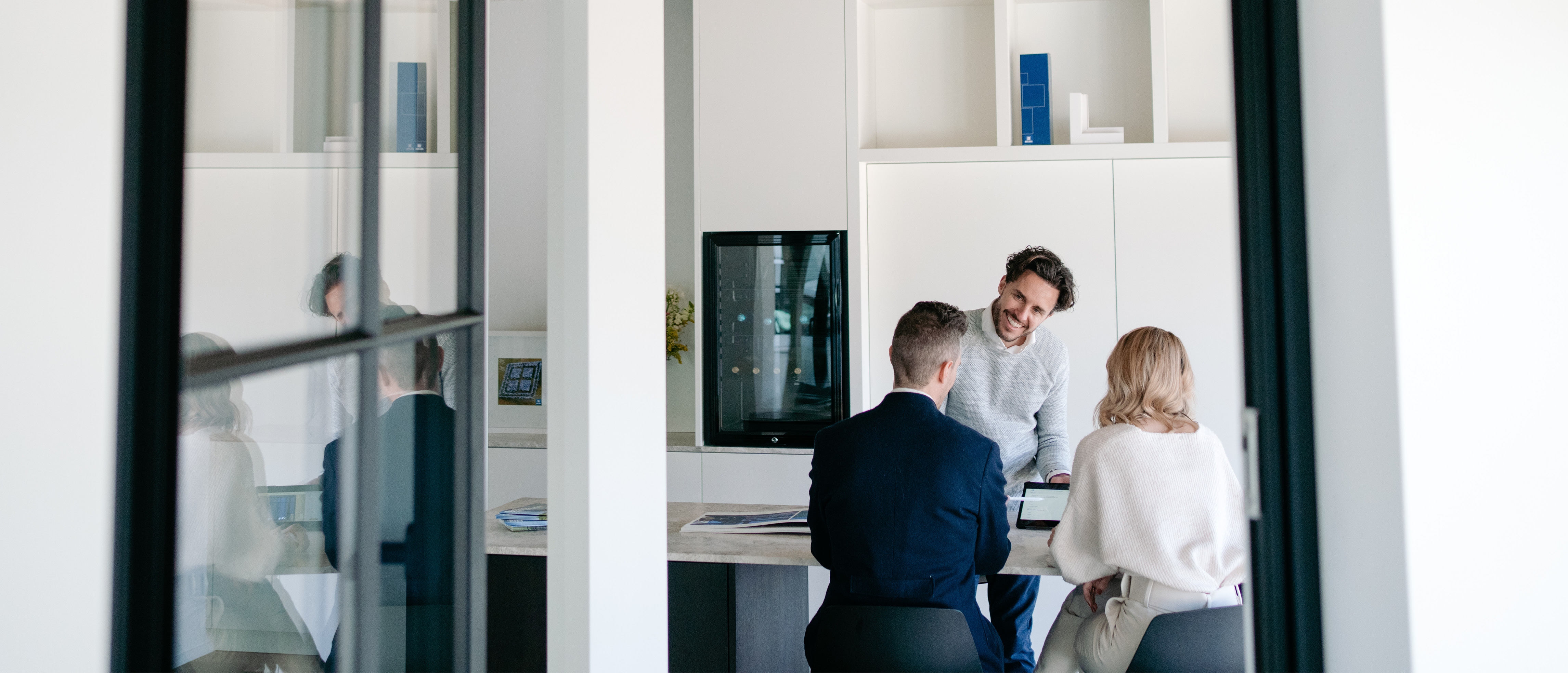 L'image montre un espace de bureau moderne avec de grandes châssis en verre et des cadres noirs élégants. Les châssis offrent une vue claire sur la pièce où se déroule une réunion. Le design est minimaliste, mettant l'accent sur des lignes épurées et un espace ouvert.